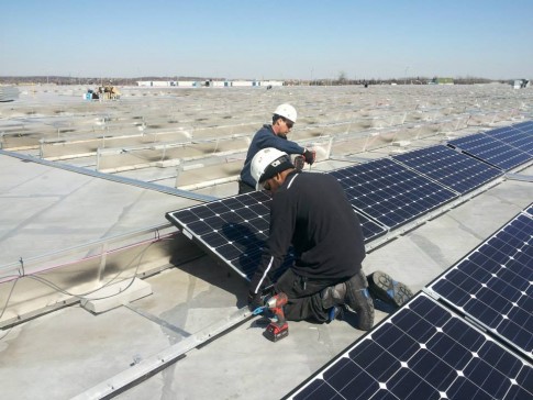 Men installing solar panels on a rooftop for SolarShare renewable energy co-operative